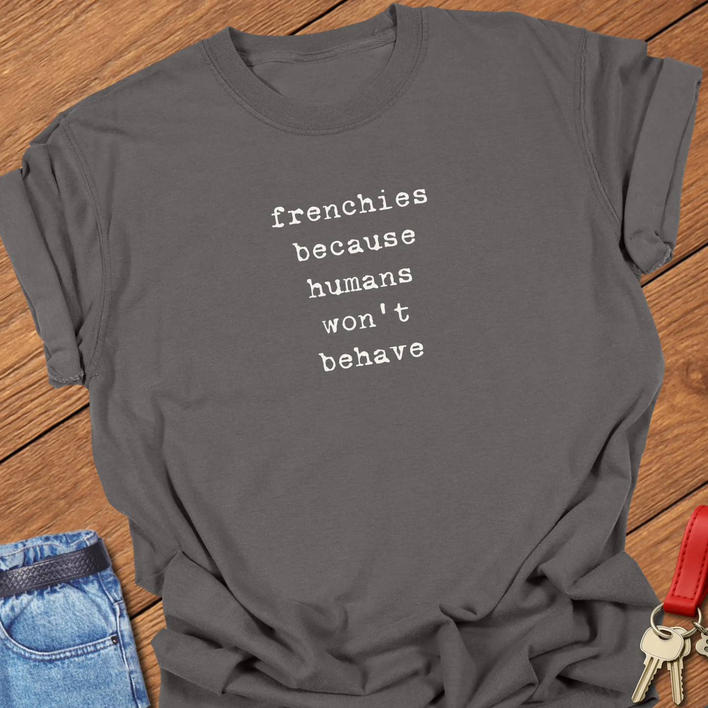 A Comfort Colors® t-shirt in Pepper featuring the phrase "Frenchies Because Humans Won't Behave" in elegant serif typography.