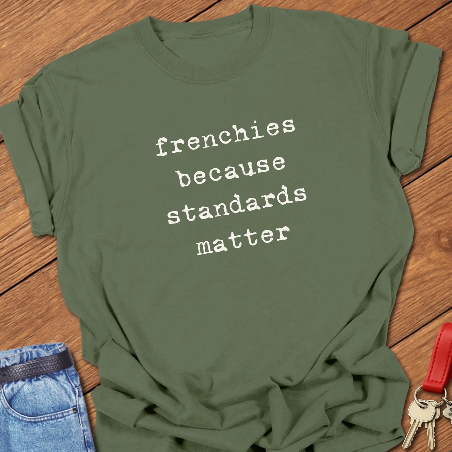 Typewriter-style typography featuring the slogan "Frenchies Because Standards Matter" printed on a Comfort Colors® garment-dyed t-shirt in Moss color.