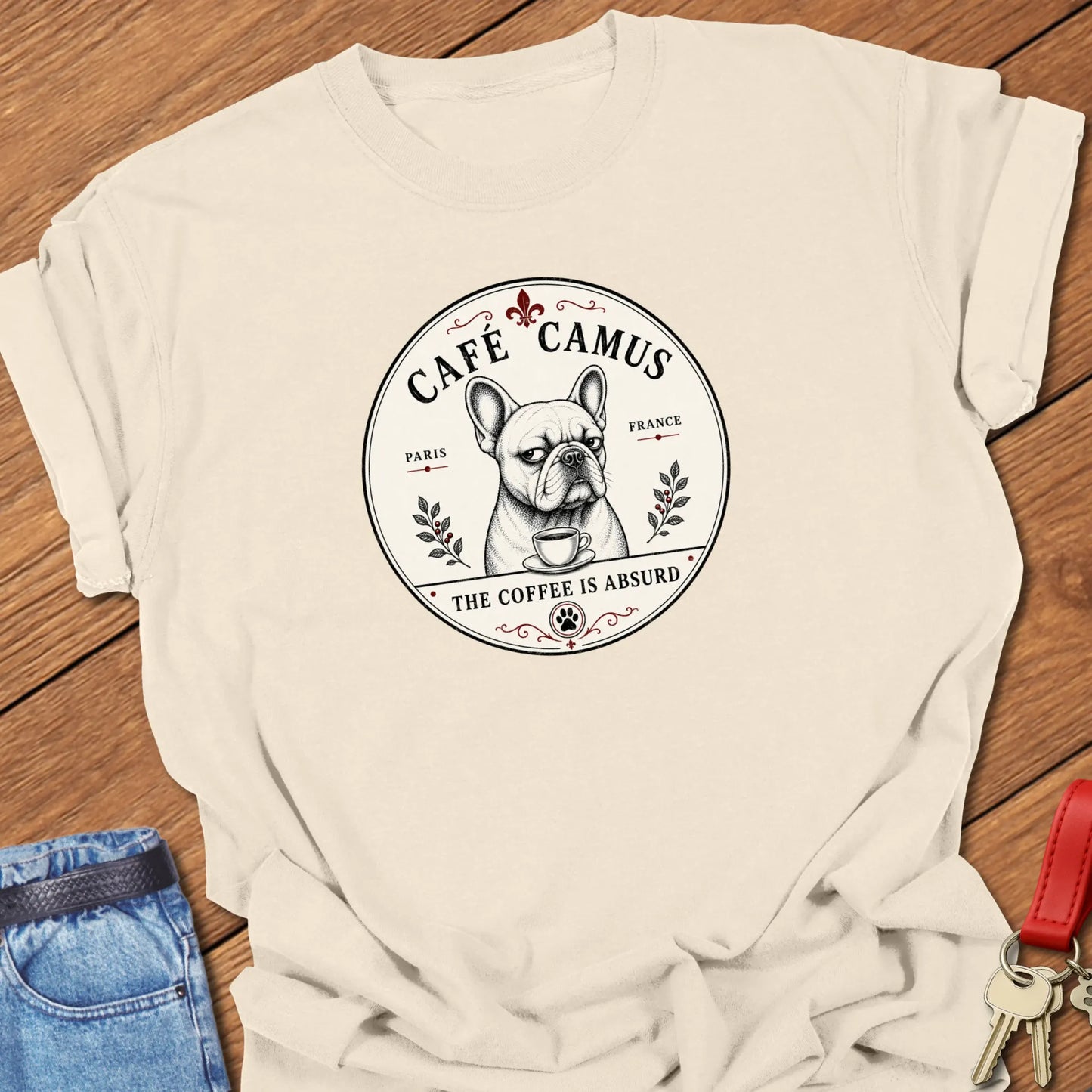 Absurd Coffee French Bulldog graphic t-shirt featuring Café Camus artwork and "The Coffee Is Absurd" slogan in Ivary color.