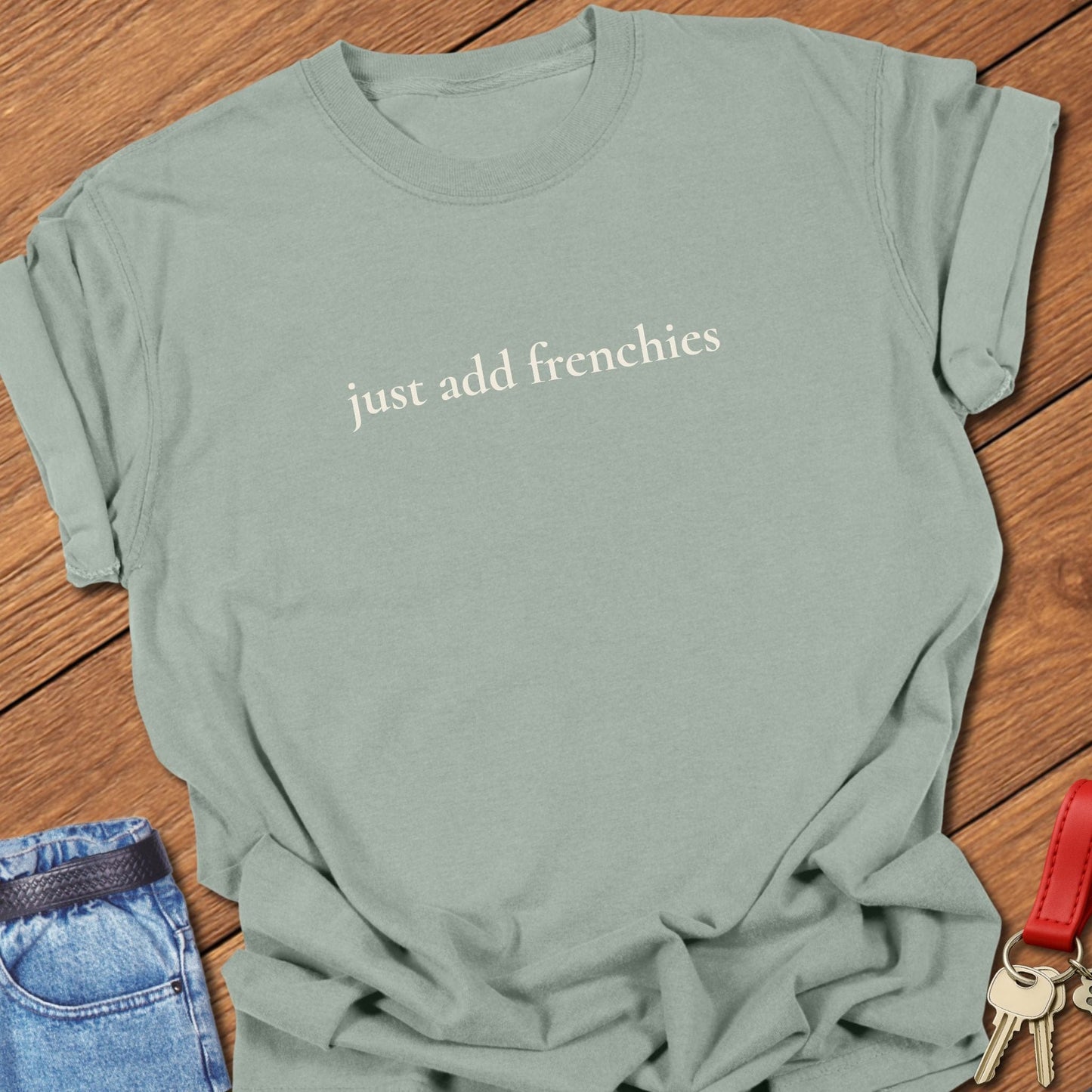 Lowercase serif text reading “just add frenchies” printed on a Comfort Colors bay t shirt.
