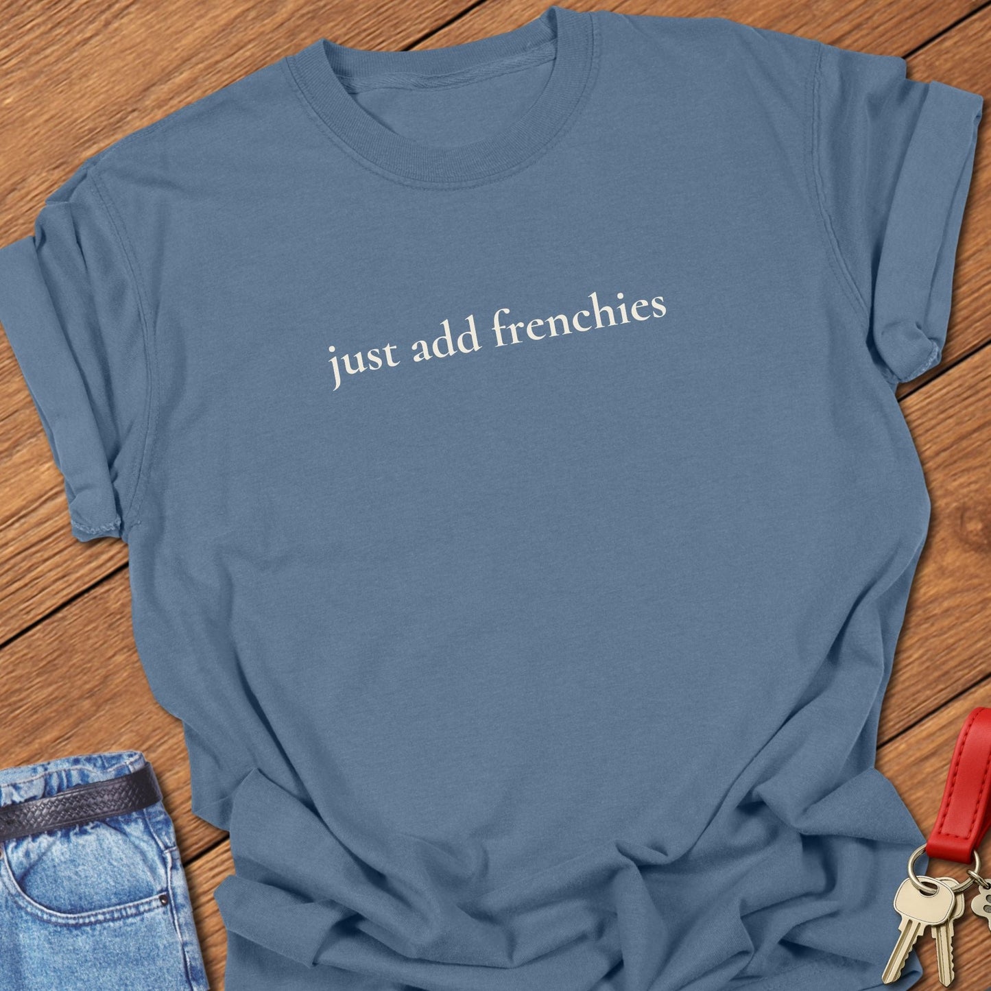 Lowercase serif text reading “just add frenchies” printed on a Comfort Colors blue jean t shirt.
