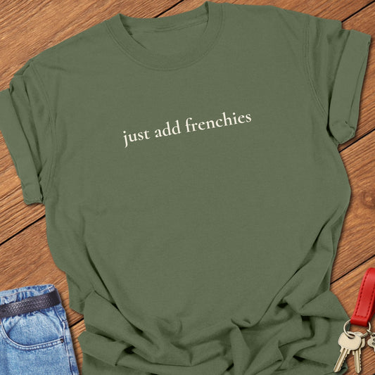 Lowercase serif text reading “just add frenchies” printed on a Comfort Colors moss t shirt.
