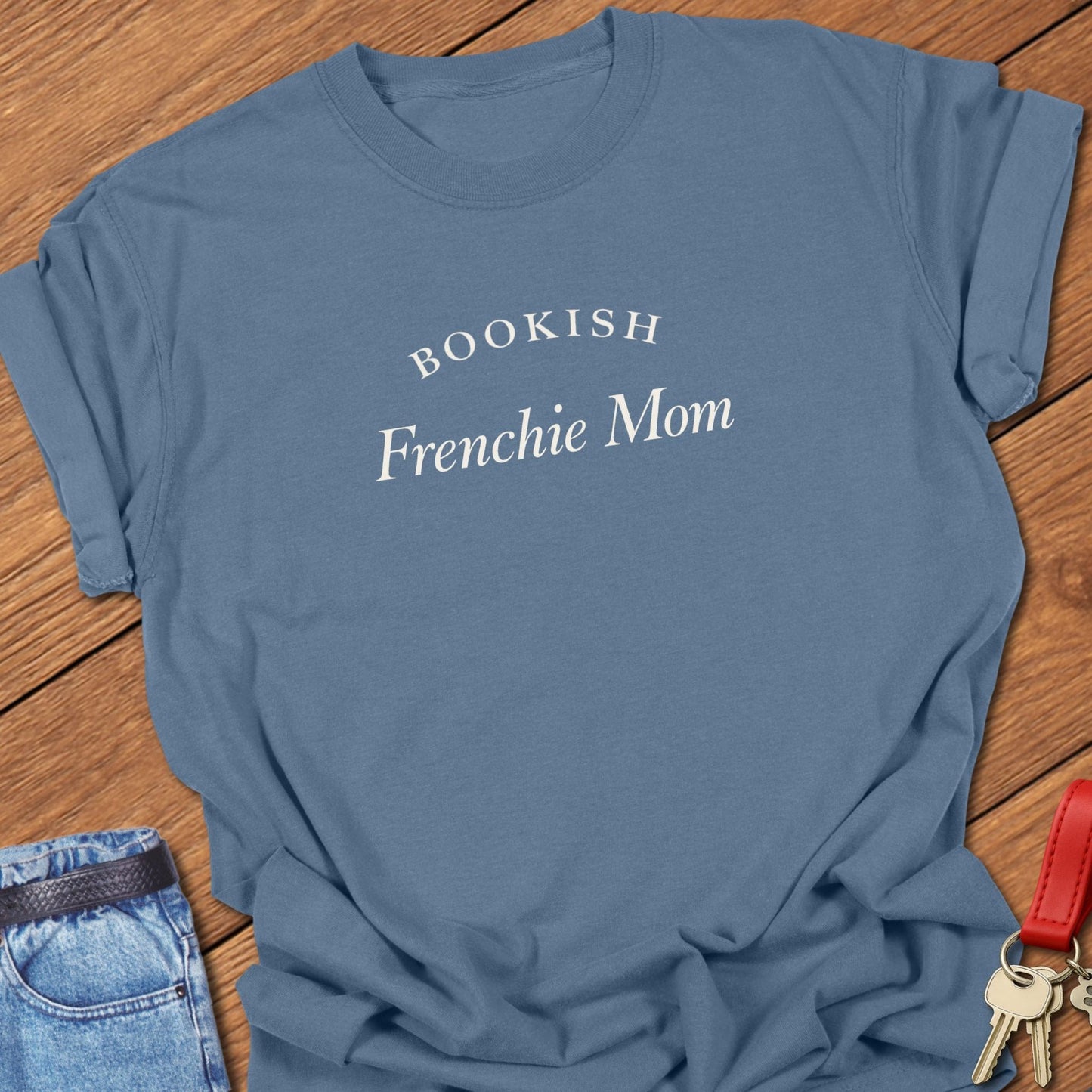 Black serif text reading “Bookish Frenchie Mom” printed on a Comfort Colors t shirt in blue jean