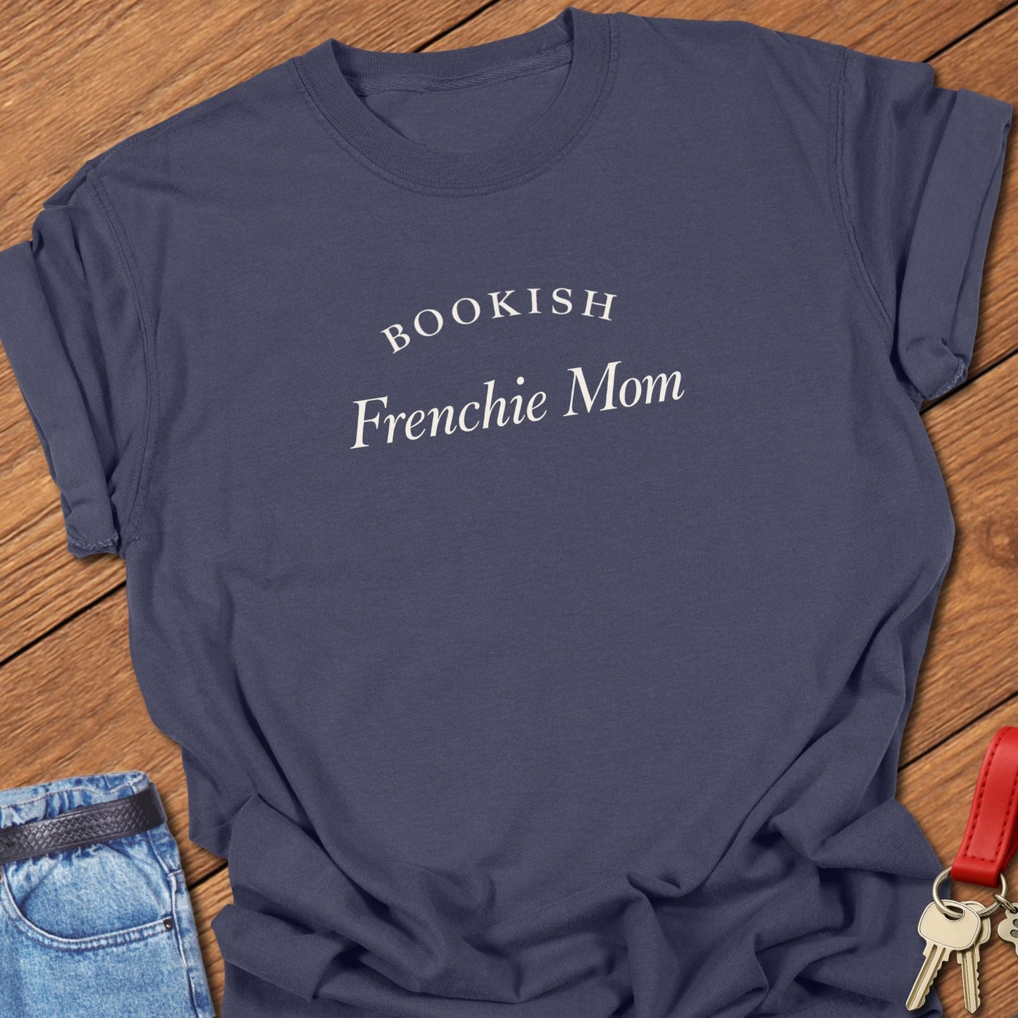 Black serif text reading “Bookish Frenchie Mom” printed on a Comfort Colors t shirt in navy