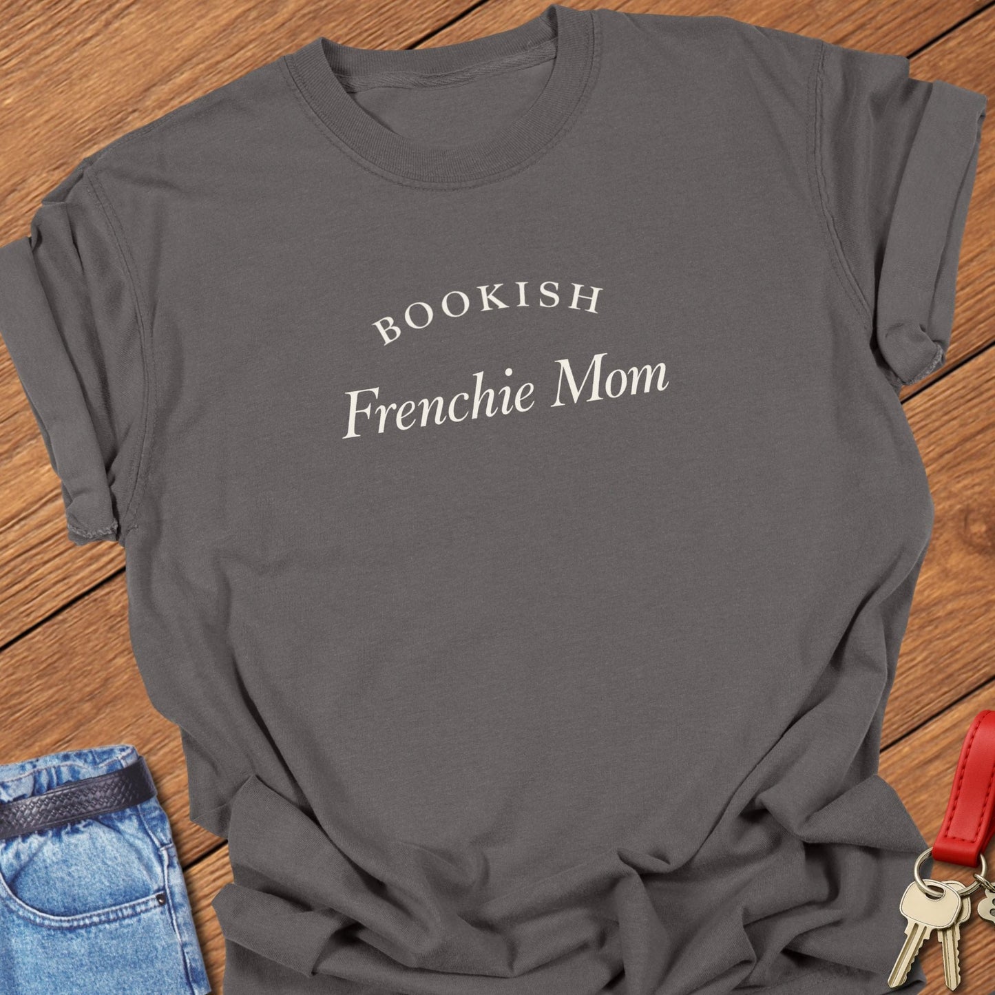 Black serif text reading “Bookish Frenchie Mom” printed on a Comfort Colors t shirt in pepper
