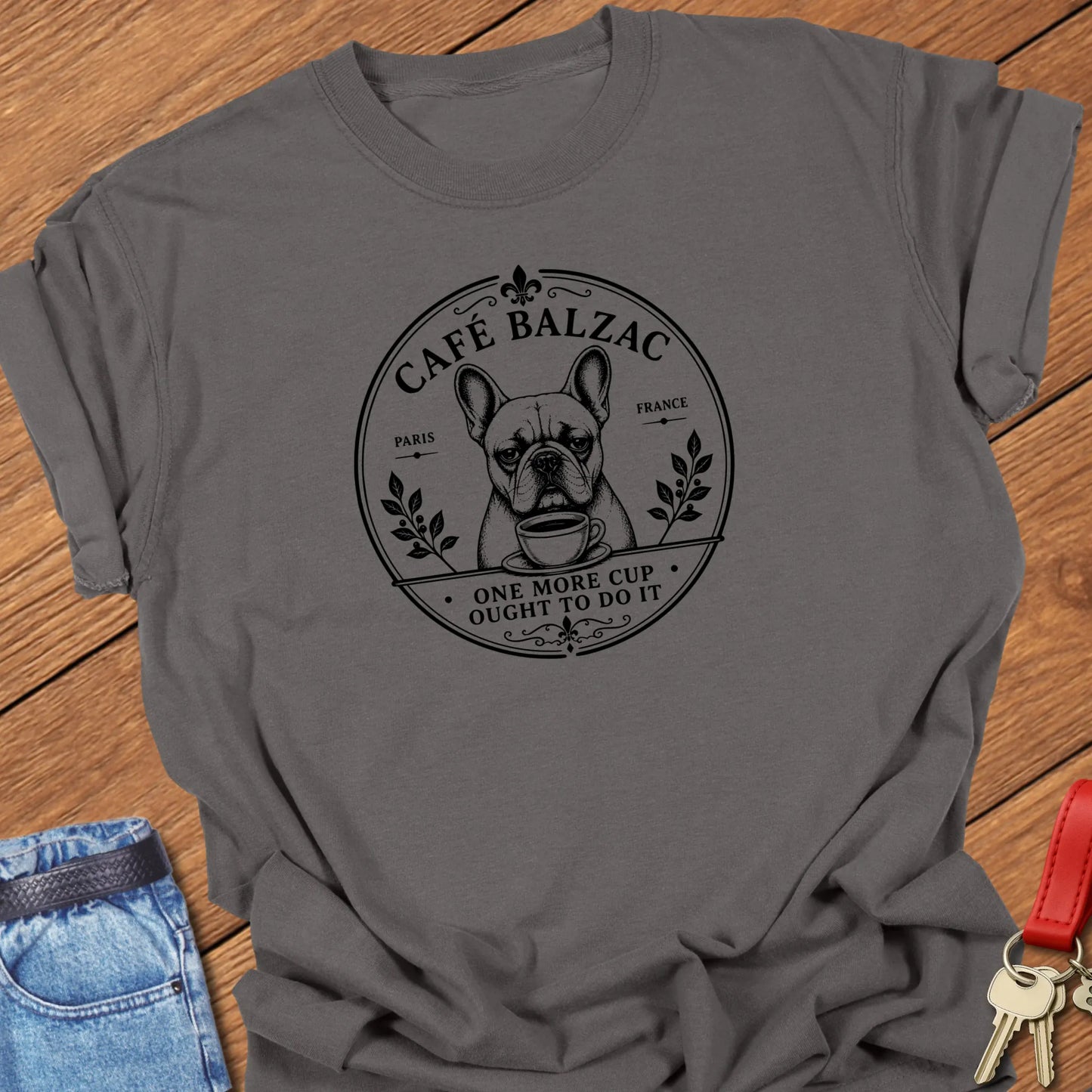 Café Balzac French Bulldog graphic t-shirt featuring "One More Cup Ought To Do It" slogan with vintage Paris café artwork inspired by literary coffee culture in Pepper color.
