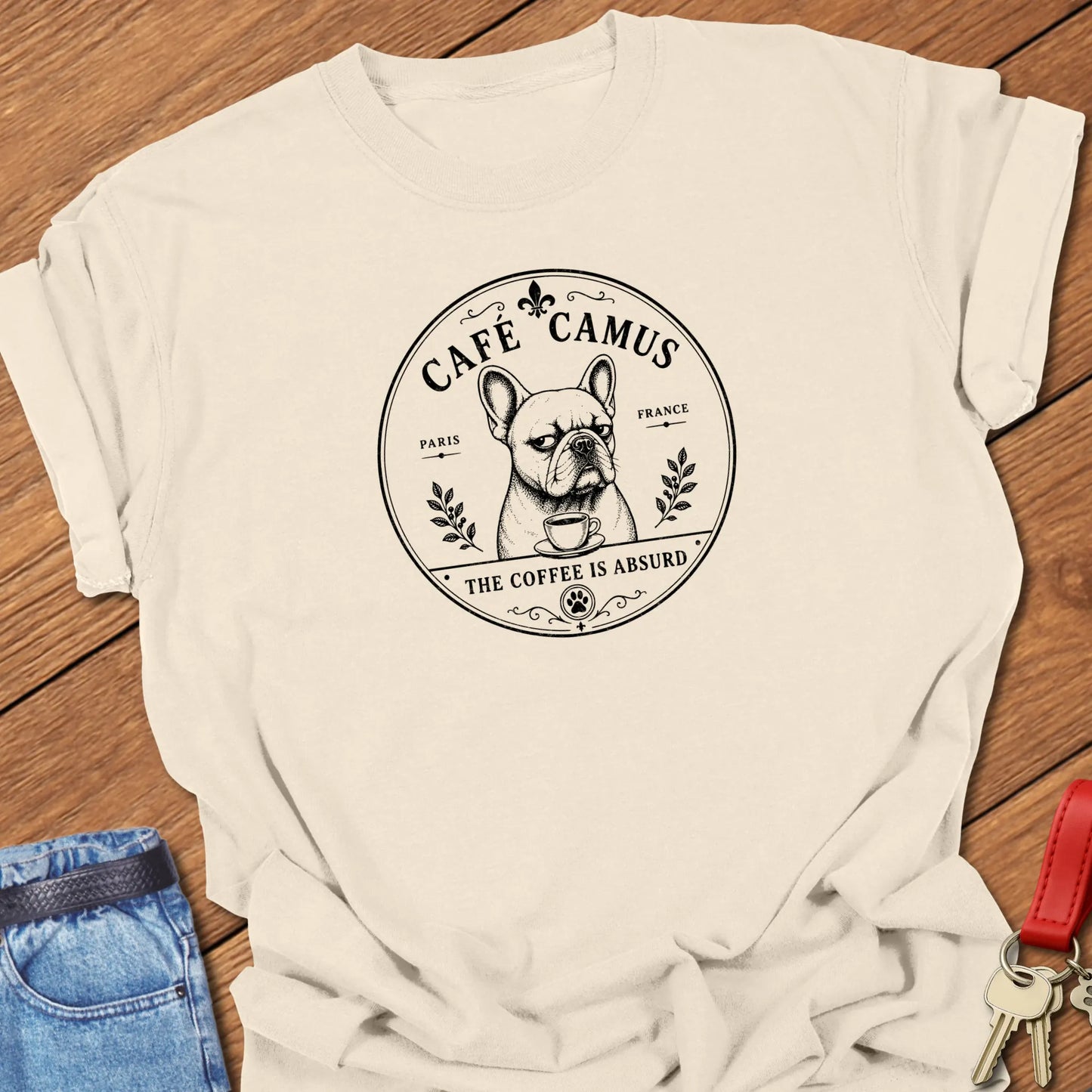 Café Camus French Bulldog literary coffee t-shirt featuring the slogan "The Coffee Is Absurd" in Ivory color with vintage Paris café-inspired artwork.
