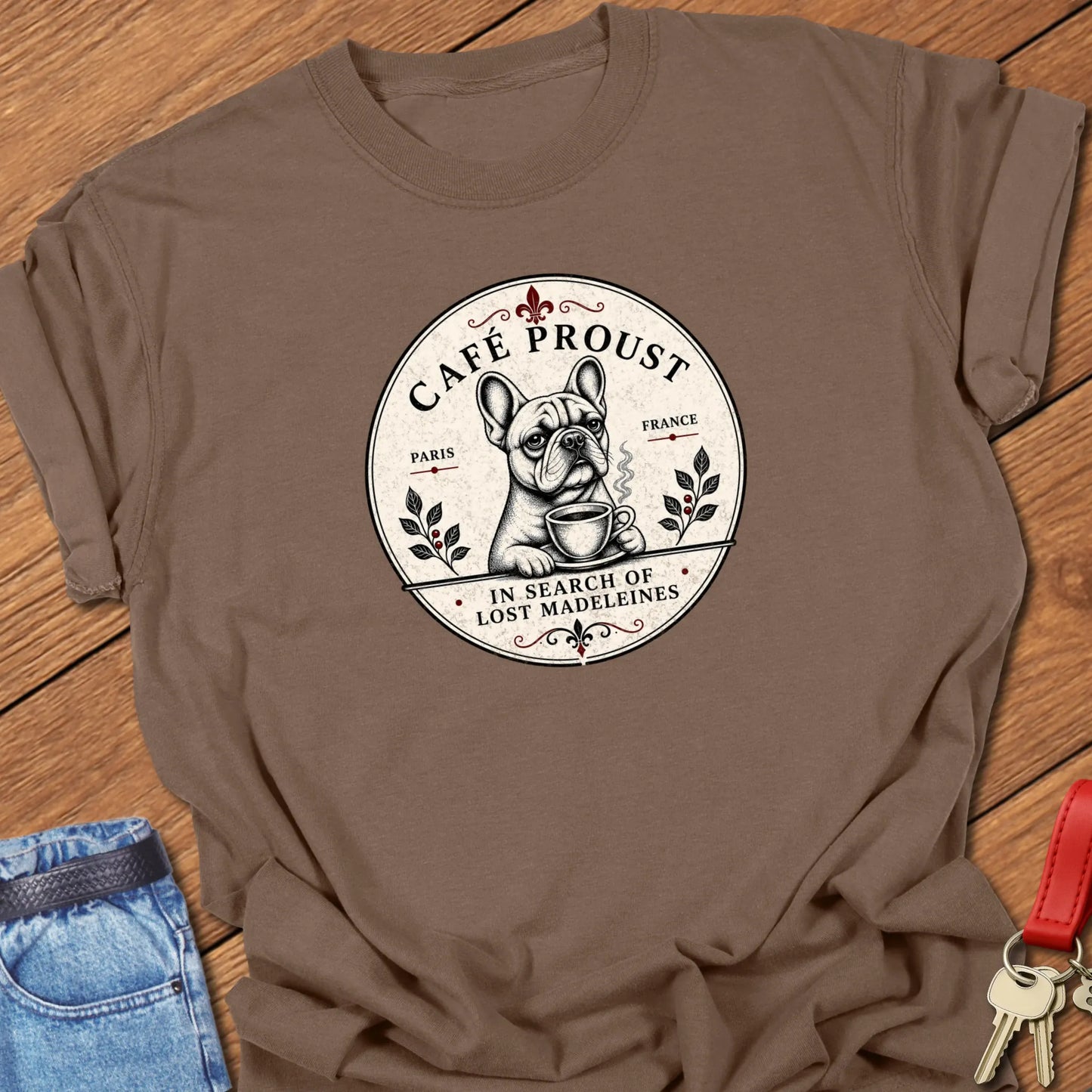Café Proust French Bulldog graphic t-shirt featuring the phrase "In Search of Lost Madeleines" with vintage Paris café artwork in Espresso color.