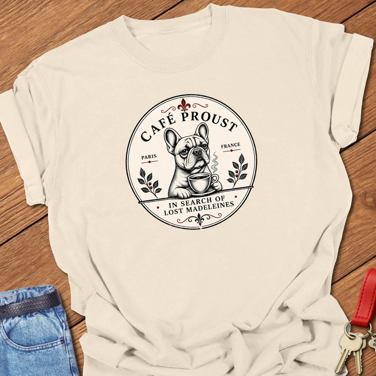 Café Proust French Bulldog graphic t-shirt featuring the phrase "In Search of Lost Madeleines" with vintage Paris café artwork in Ivory color.