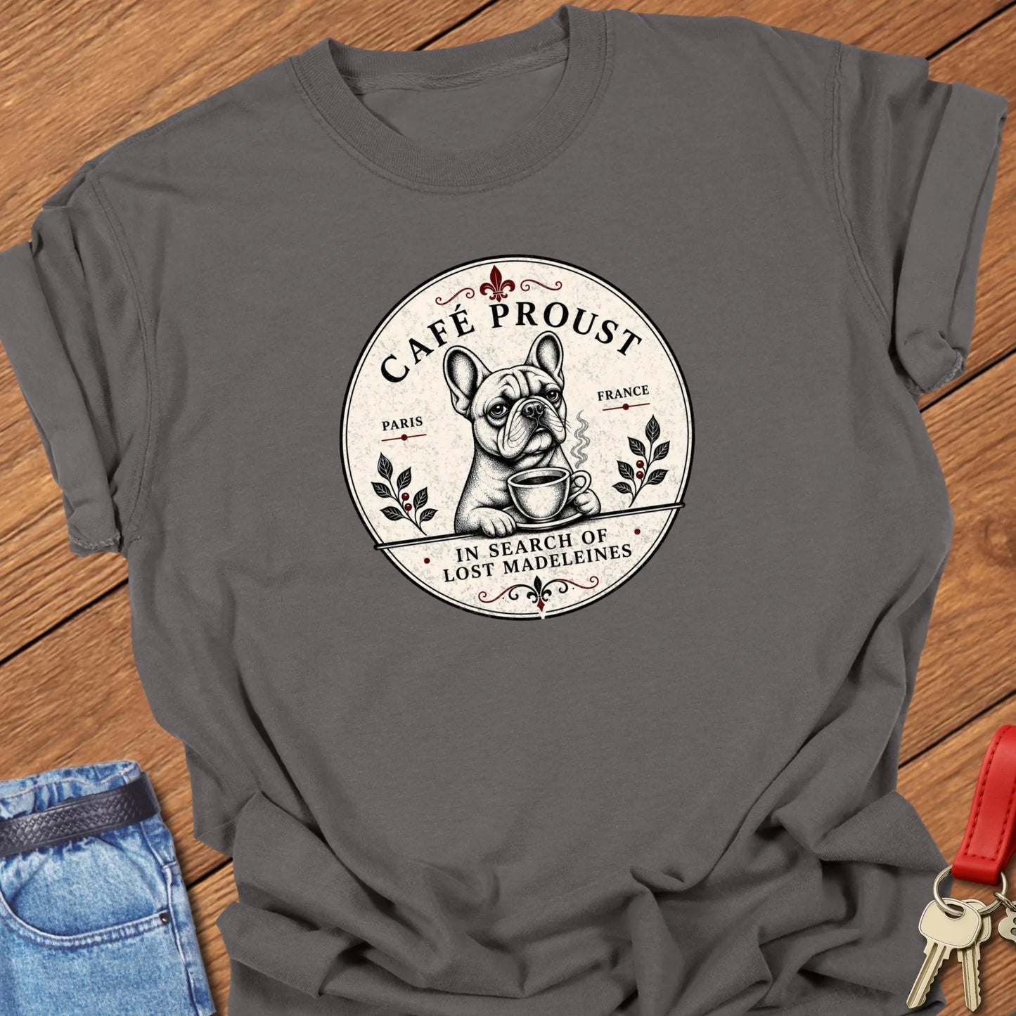Café Proust French Bulldog graphic t-shirt featuring the phrase "In Search of Lost Madeleines" with vintage Paris café artwork in Pepper color.