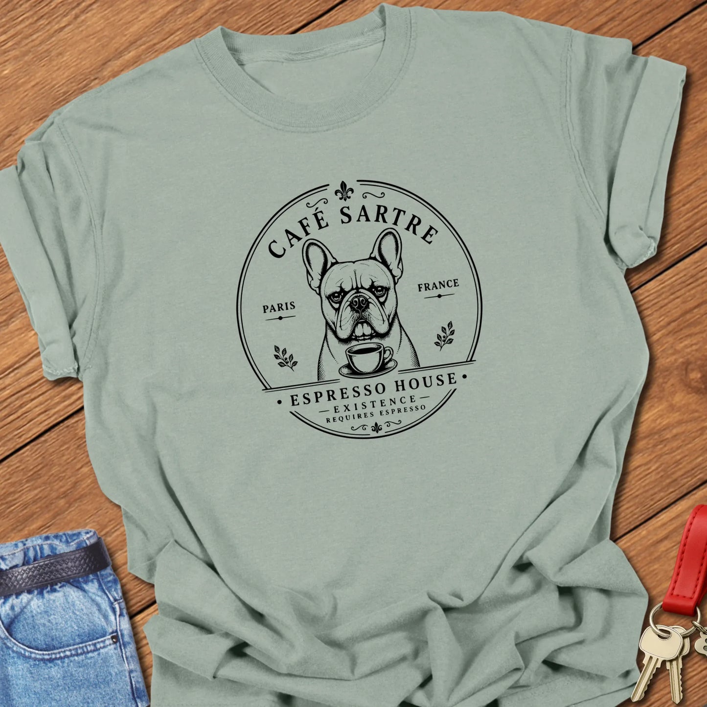 Café Sartre French Bulldog graphic t-shirt featuring "Existence Requires Espresso" slogan with vintage Paris café artwork in Bay color.