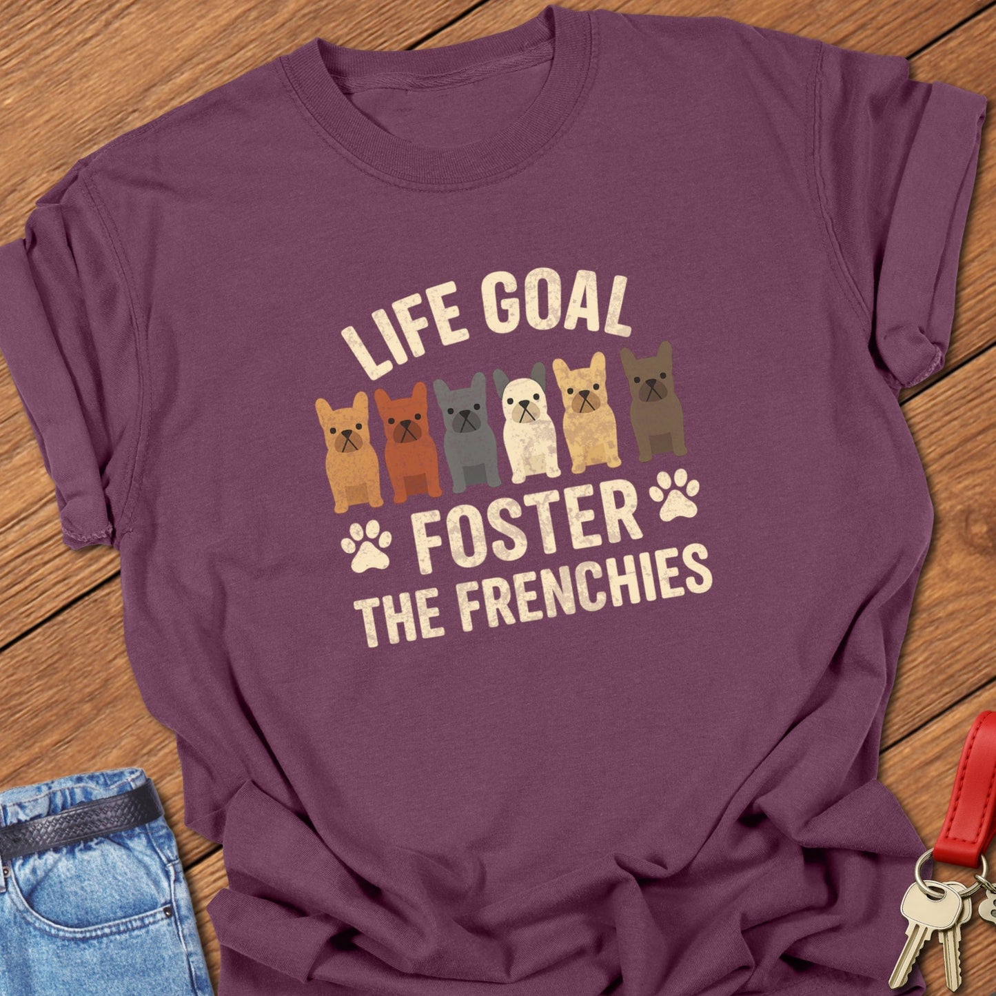 French bulldog foster illustration with multiple Frenchie graphics and bold life goal typography printed on berry Comfort Colors t shirt