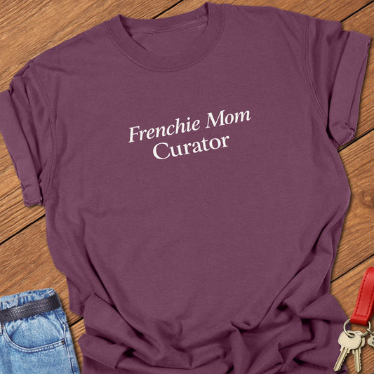 Minimalist serif text design reading “Frenchie Mom Curator” on garment-dyed Comfort Colors t shirt in berry.
