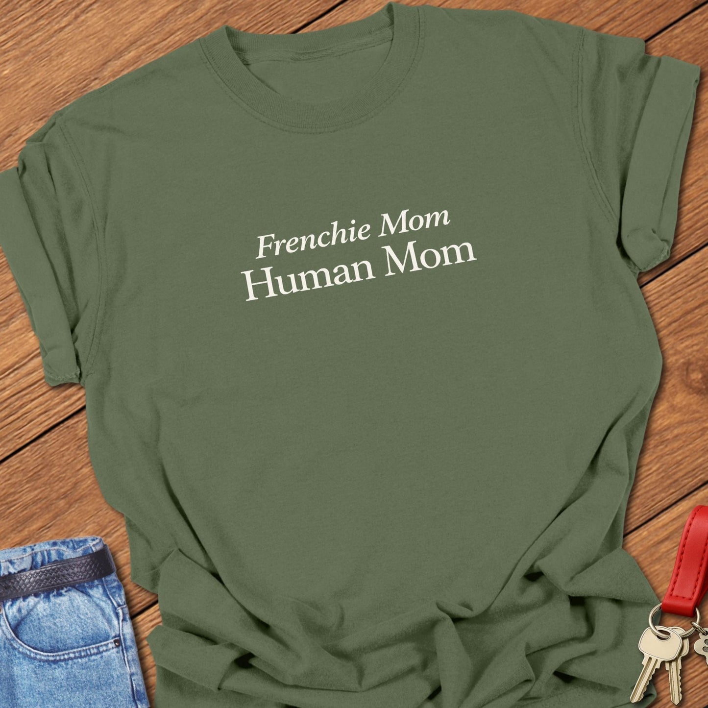 Comfort Colors garment-dyed Frenchie mom t shirt with ivory serif “Frenchie Mom Human Mom” typography on a moss tee, designed for women balancing motherhood and French bulldog life.
