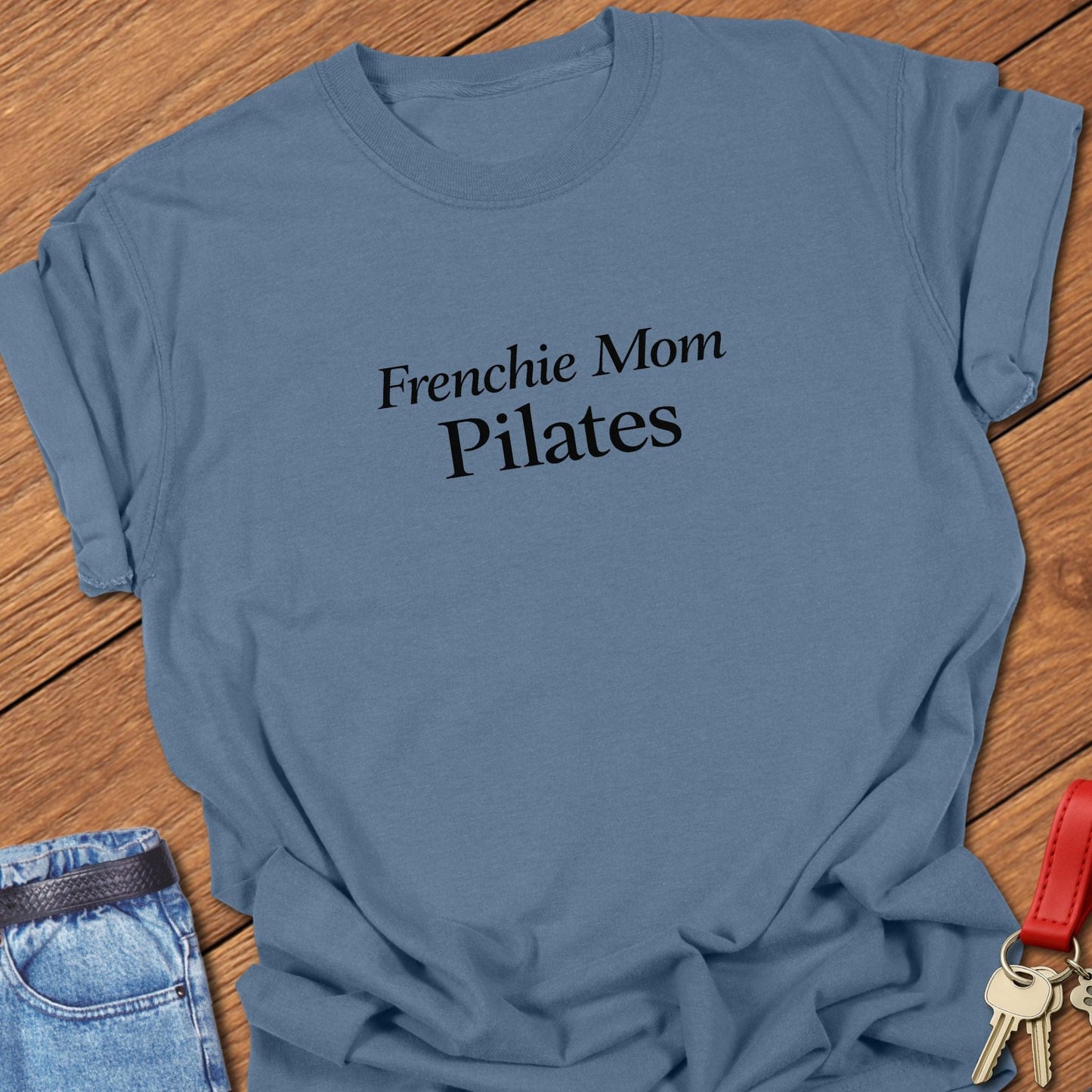 Frenchie Mom Pilates text design printed in black serif typography on a garment-dyed Comfort Colors 1717 t shirt in blue jean.
