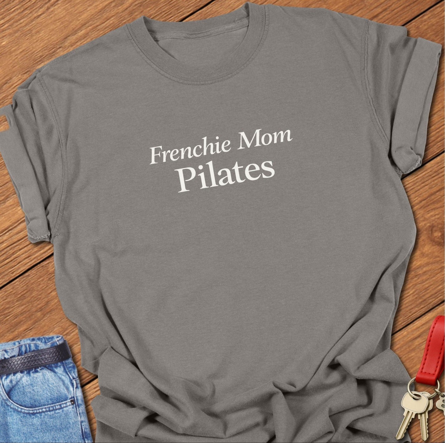 Frenchie Mom Pilates text design printed in black serif typography on a garment-dyed Comfort Colors 1717 t shirt in grey.
