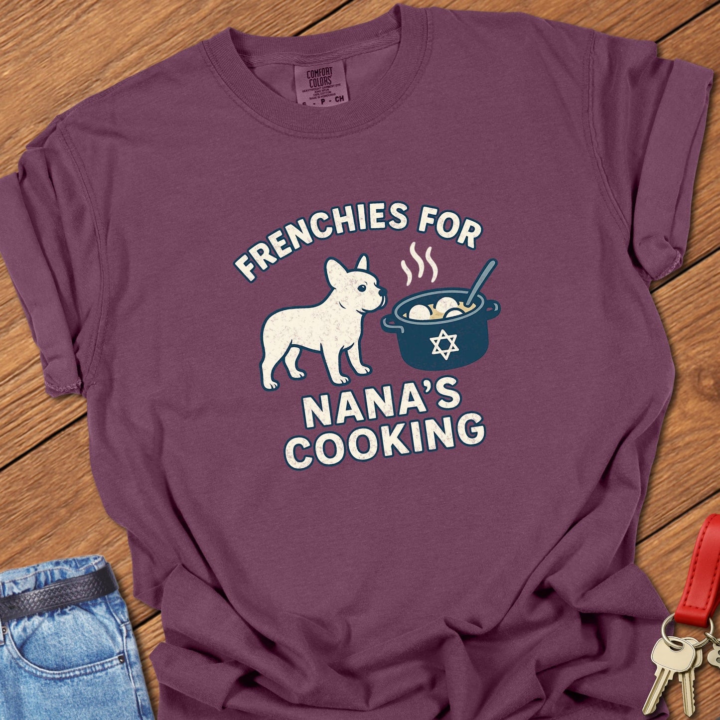 French bulldog humorous Jewish food illustration with Nana’s cooking pot graphic and playful slogan printed on berry Comfort Colors t shirt