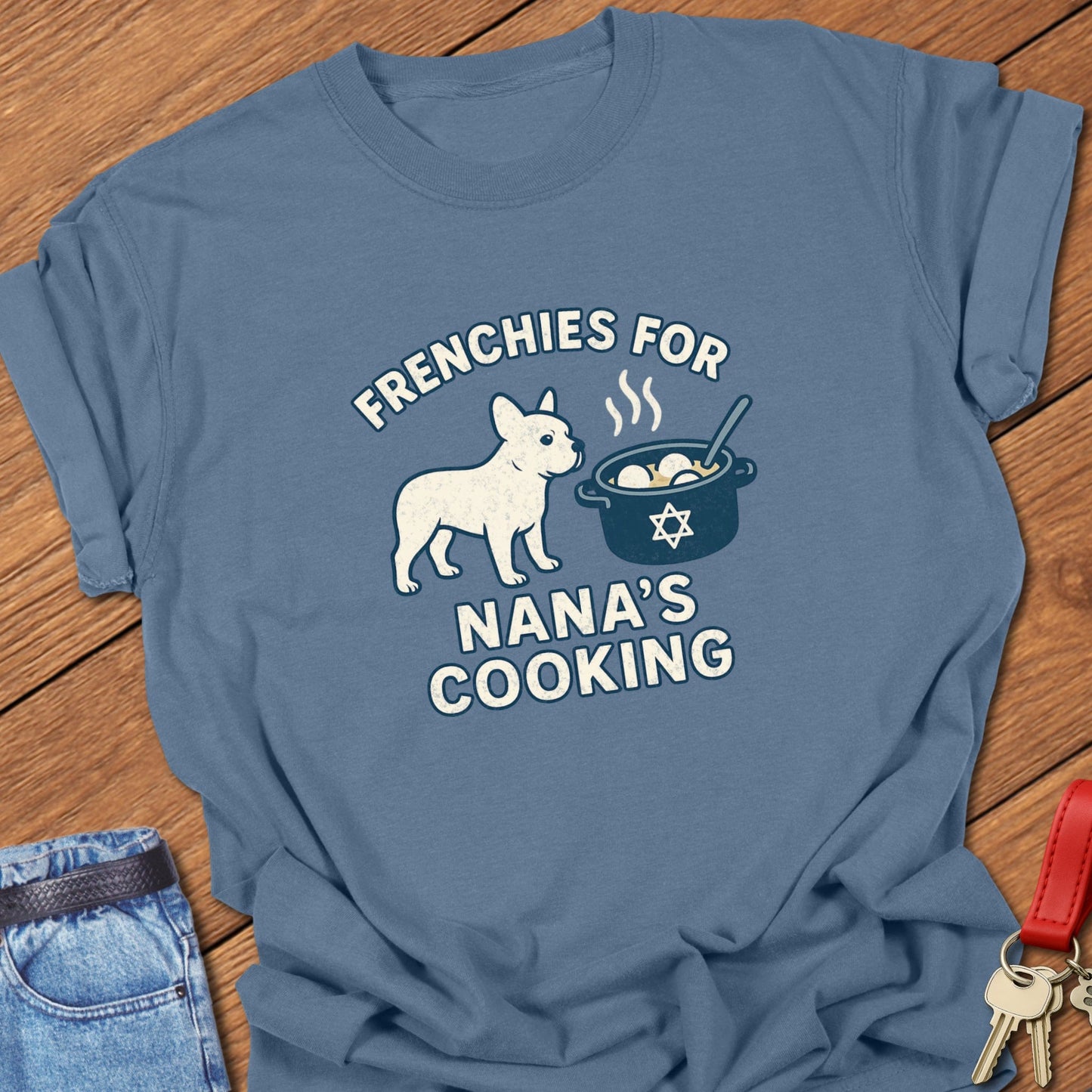 French bulldog humorous Jewish food illustration with Nana’s cooking pot graphic and playful slogan printed on blue jean Comfort Colors t shirt
