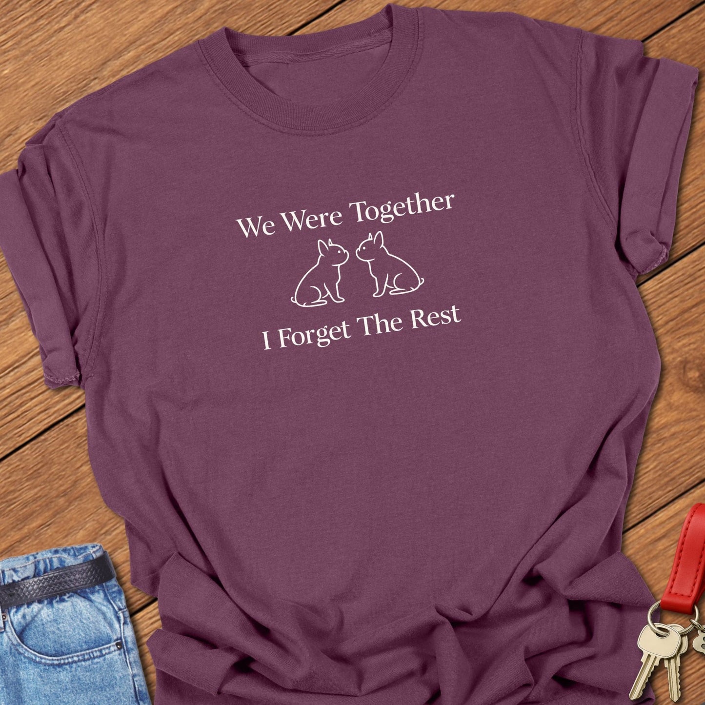 Ivory serif text reading “We Were Together I Forget The Rest” inspired by Walt Whitman, with two minimalist French bulldog silhouettes printed on a berry Comfort Colors t shirt.
