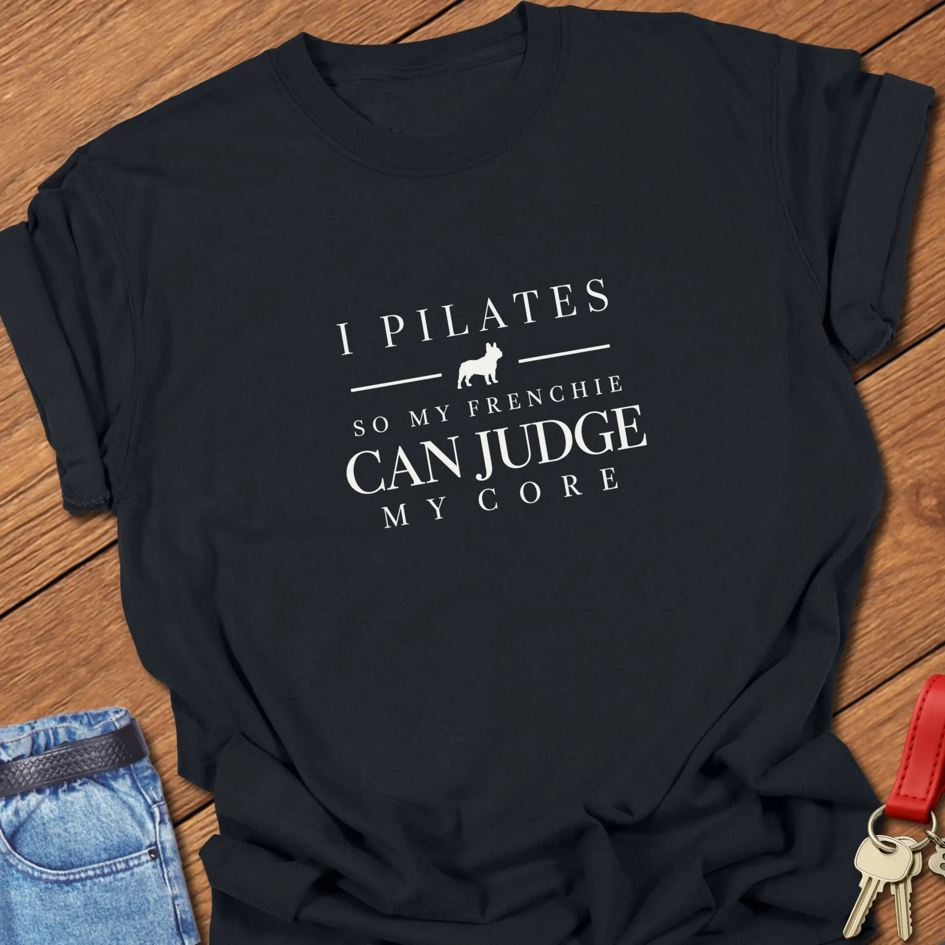 I Pilates So My Frenchie Can Judge My Core slogan featuring a French Bulldog silhouette. On a Comfort Colors 1717 cotton shirt in Black color.