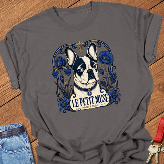 Art Nouveau-inspired French Bulldog portrait surrounded by cobalt-blue floral ornamentation with the title "Le Petit Muse — Paris 1898" printed on a Comfort Colors® garment-dyed t-shirt in Pepper color.