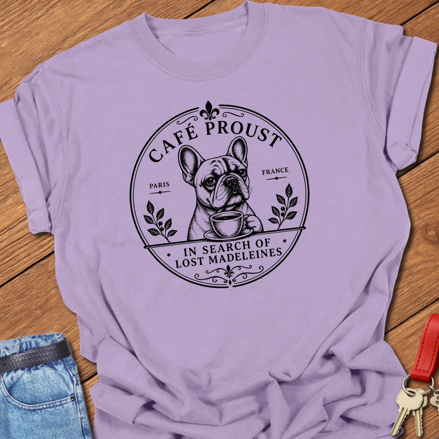 Lost Madeleines French Bulldog graphic t-shirt featuring "In Search of Lost Madeleines" literary café artwork with a thoughtful Frenchie holding a coffee cup in Orchid color.