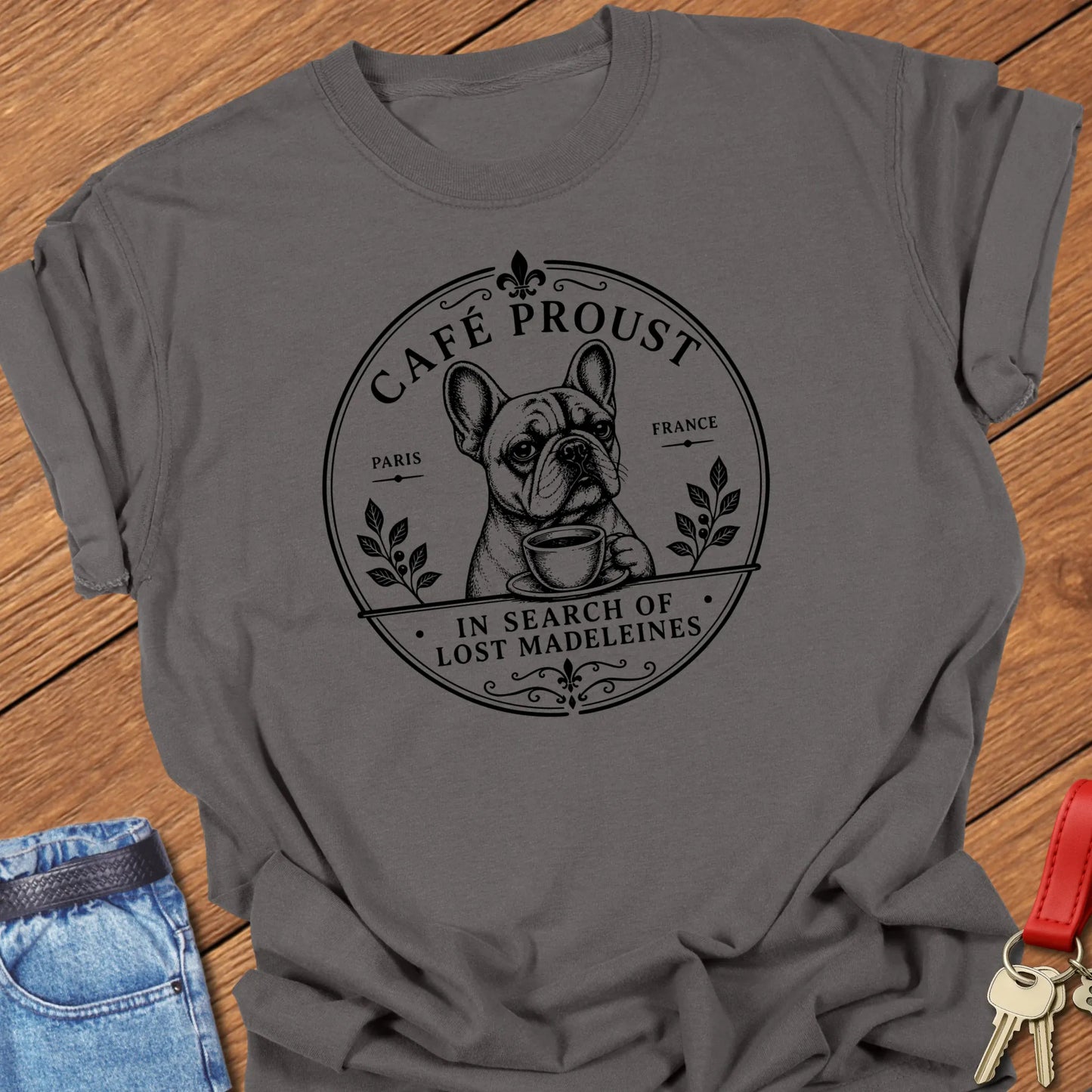 Lost Madeleines French Bulldog graphic t-shirt featuring "In Search of Lost Madeleines" literary café artwork with a thoughtful Frenchie holding a coffee cup in Pepper color.
