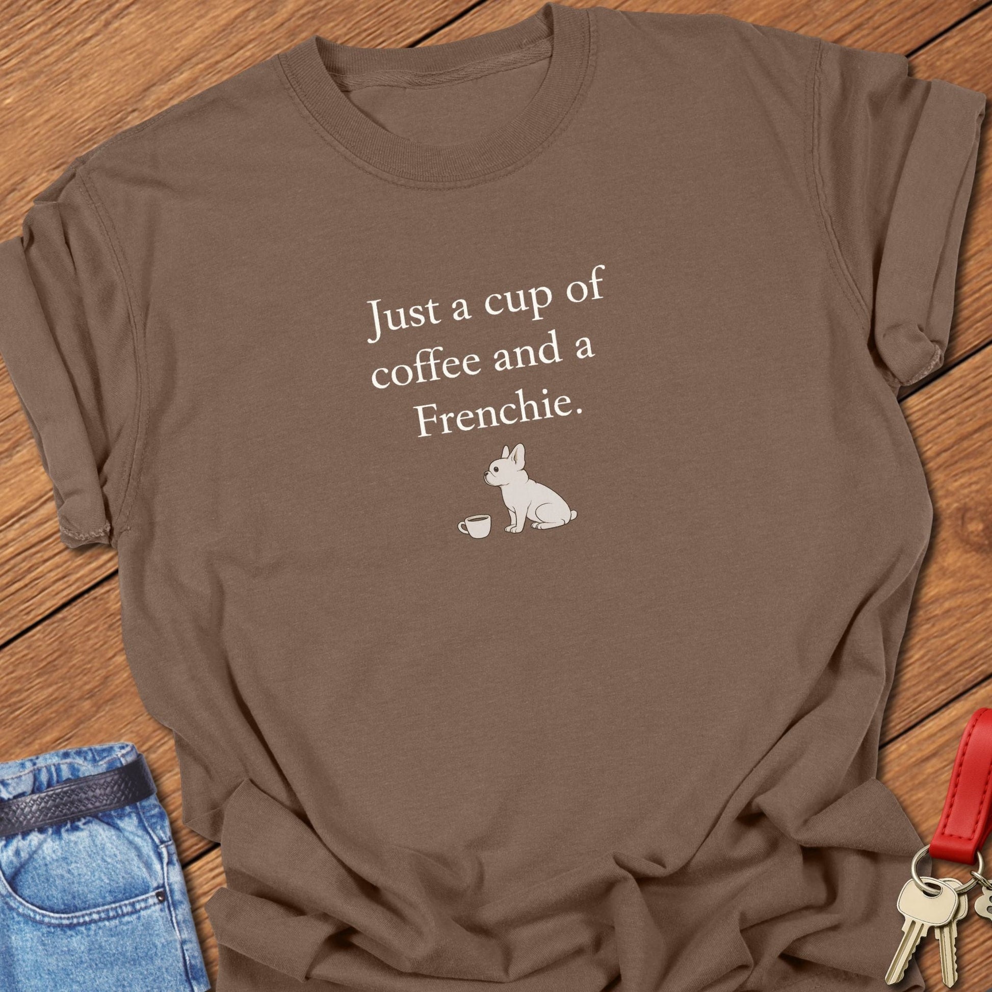French bulldog sitting beside a coffee cup with text reading “Just a cup of coffee and a Frenchie” on a minimalist graphic T-shirt in espresso.
