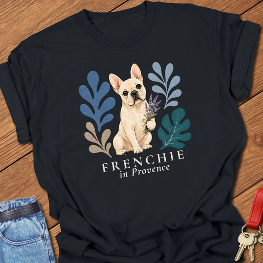 Cream French Bulldog holding a lavender bouquet surrounded by botanical artwork with the phrase "Frenchie in Provence" printed on a Comfort Colors® garment-dyed t-shirt in Black color.