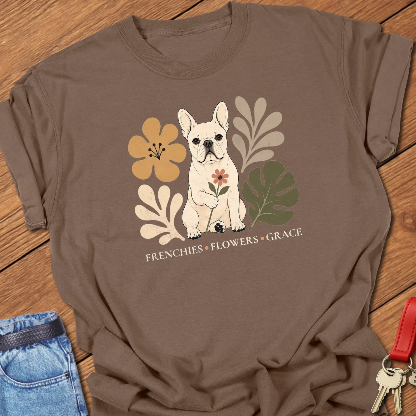 Cream French Bulldog holding a flower surrounded by modern botanical artwork with the phrase "Frenchies • Flowers • Grace" printed on a Comfort Colors® garment-dyed t-shirt in Espresso color.