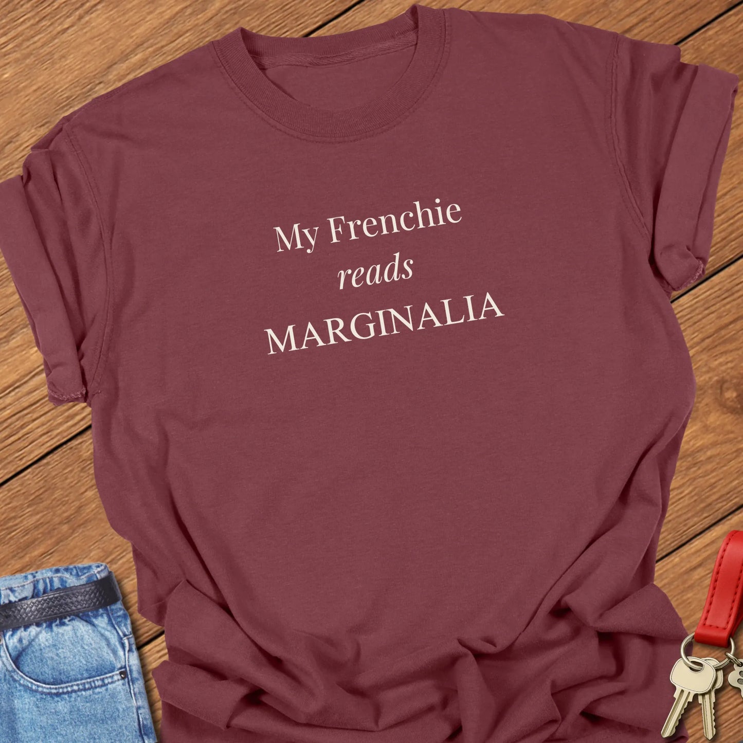 Reads Marginalia T Shirt featuring the phrase "My Frenchie Reads Marginalia" in elegant ivory typography on a Comfort Colors 1717 shirt in Brick Color.