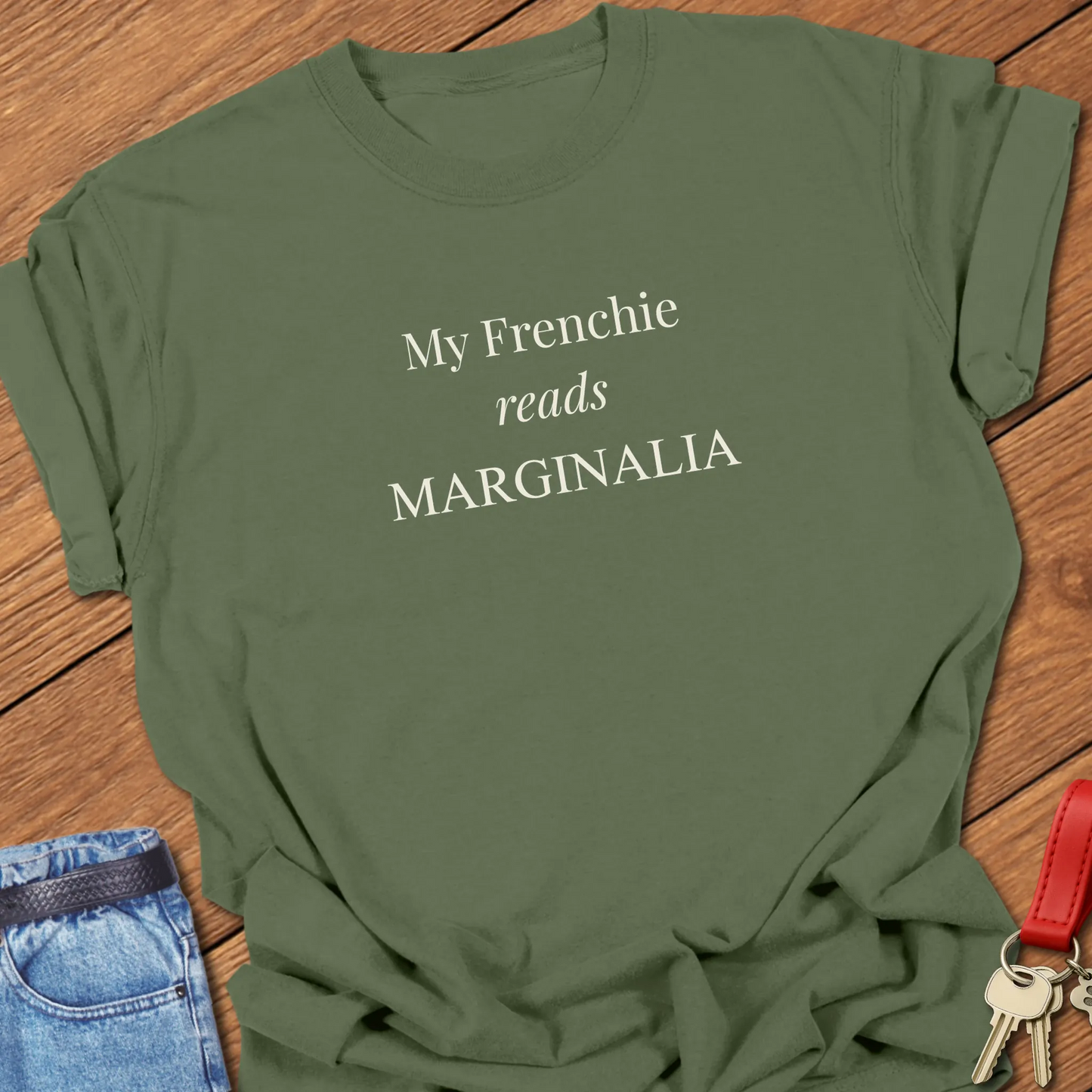 Reads Marginalia T Shirt featuring the phrase "My Frenchie Reads Marginalia" in elegant ivory typography on a Comfort Colors 1717 shirt in Moss Color.