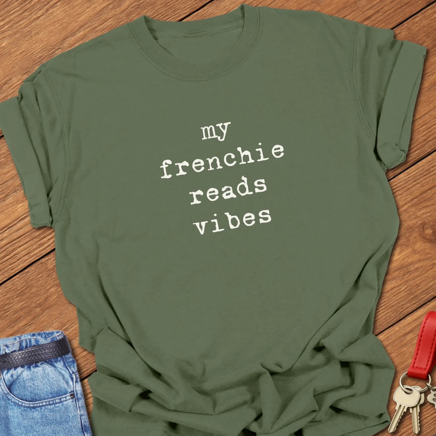 Typewriter-style typography featuring the slogan "My Frenchie Reads Vibes" printed on a Comfort Colors® garment-dyed t-shirt in Moss color.