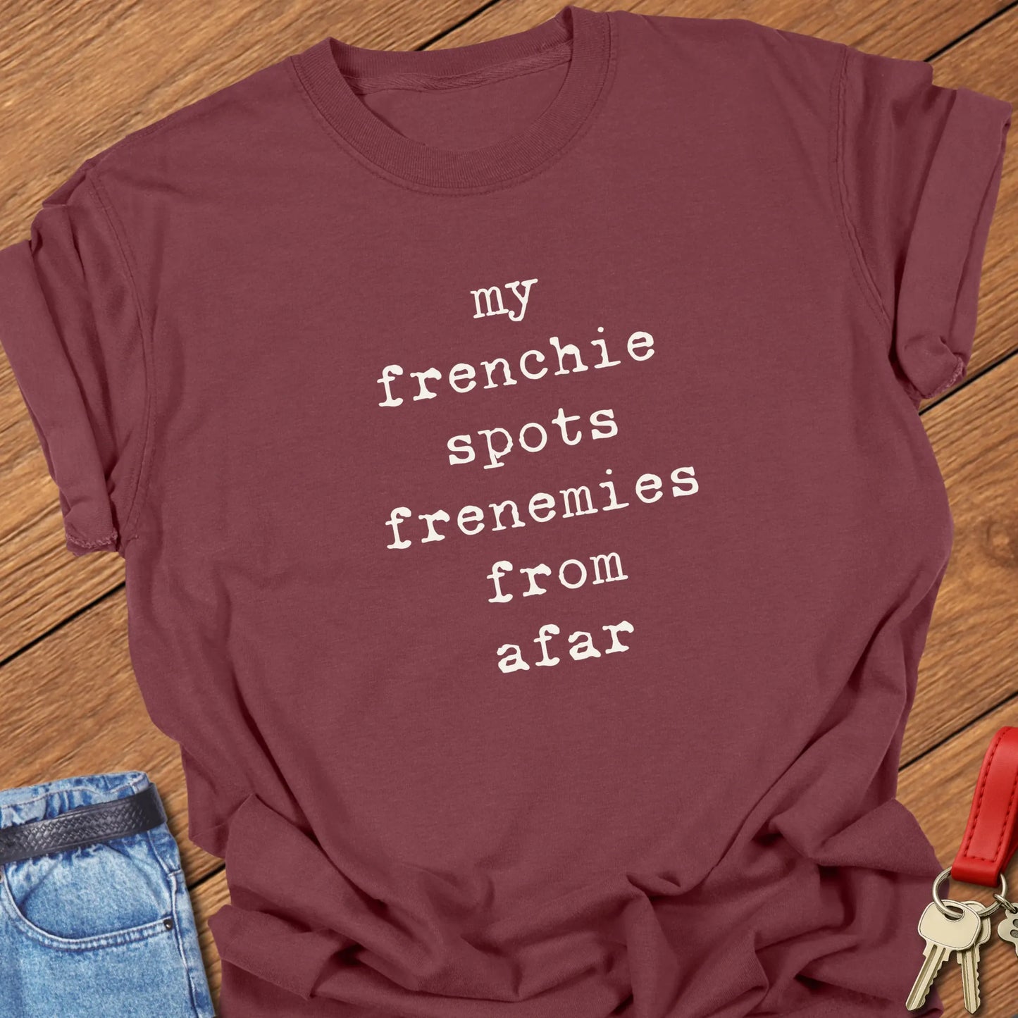 Typewriter-style typography featuring the slogan "My Frenchie Spots Frenemies From Afar" printed on a Comfort Colors® garment-dyed t-shirt in Brick color.